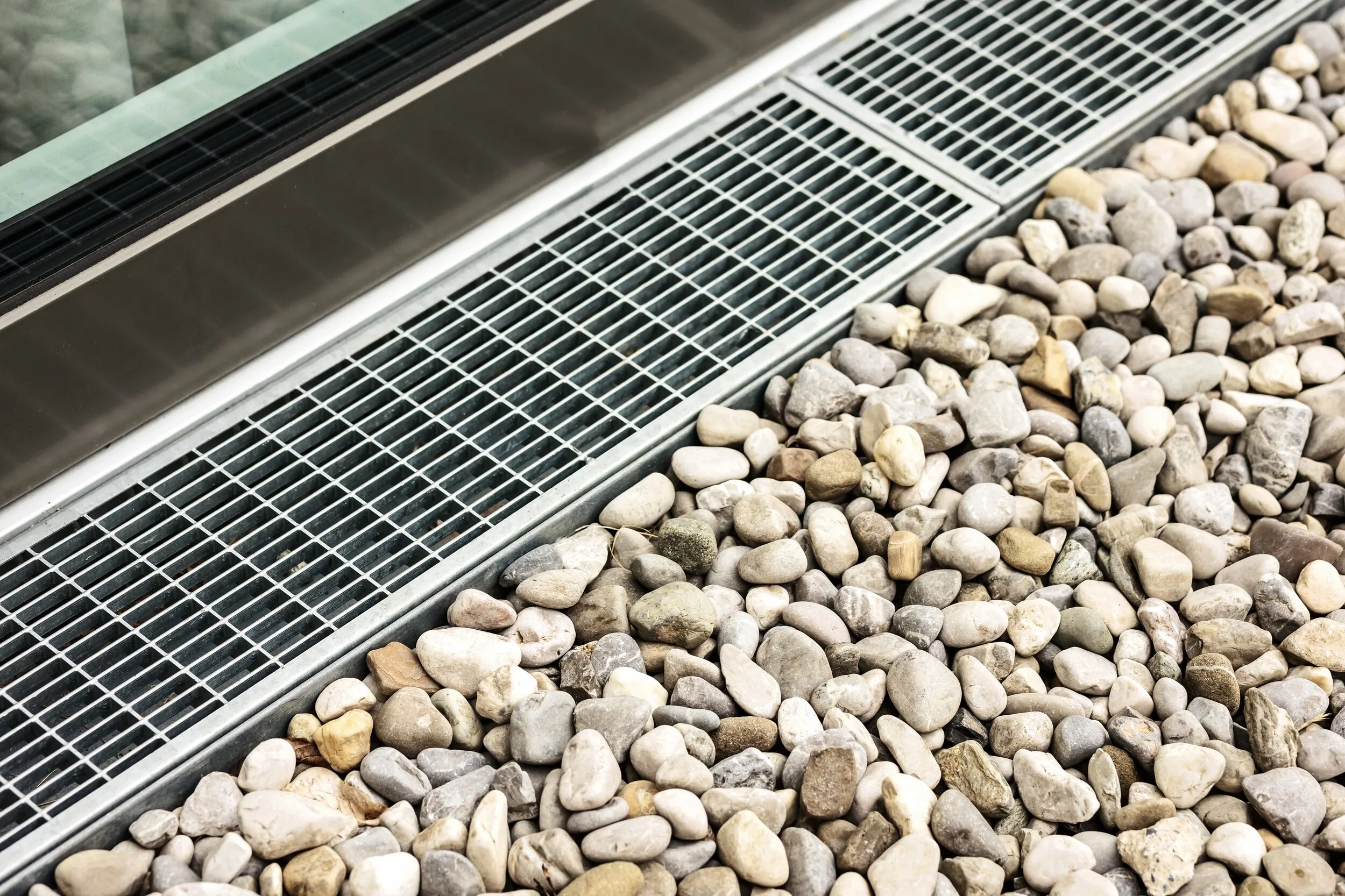 Channel drain installed along a pebble border